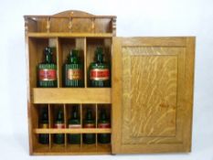 OAK MEDICINE BOTTLE CABINET containing eight green glass Latin labelled bottles, all having ribbed