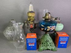 IRON BASED OIL LAMP - with floral painted blue glass reservoir, two other oil lamps, shades,