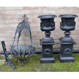 PAIR CAST IRON GARDEN URNS ON PLINTHS, decorated with scrolling foliage on laurel wreath