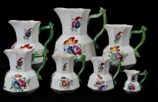 GRADUATED SET OF SEVEN DILLWYN SWANSEA POTTERY JUGS of faceted form with green enamelled twig