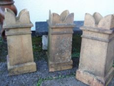 THREE TERRACOTTA TURRET TOP CHIMNEY POTS, of square section, 76cms high (3) Provenance: deceased