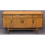 G PLAN STYLE MID-CENTURY TEAK SIDEBOARD with three drawers over four cupboard doors on a shaped