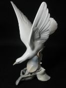LLADRO - a seabird with spread wings alighting on a tree base, 27cms H