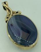 9CT GOLD OVAL PENDANT with scrolled chain loop and with blue veined agate to one side of deep blue