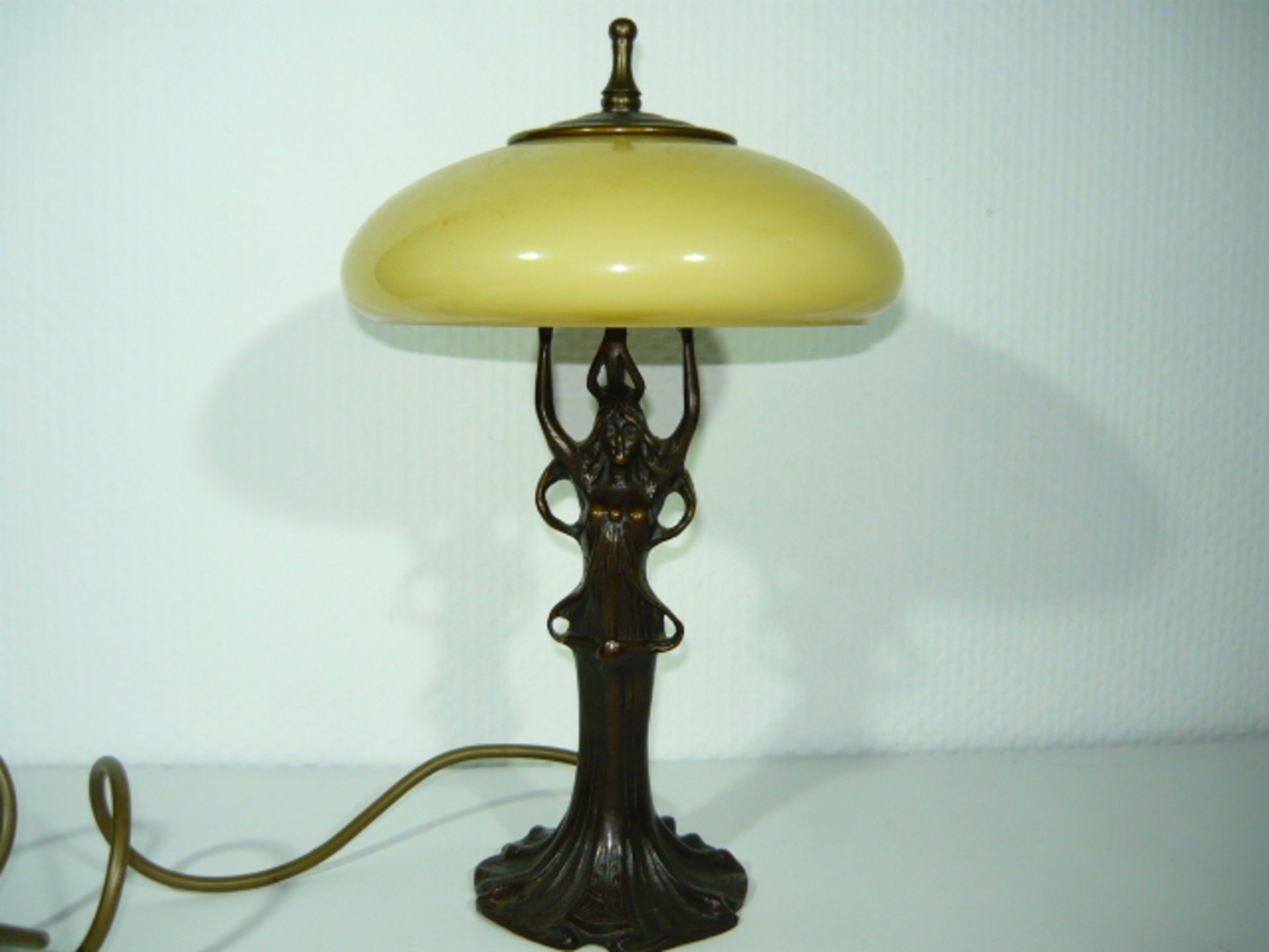 Tischlampe mit Glasschirm. Fuß in Form einer Frau im Jugendstil. Bronze. Lampe leuchtet.