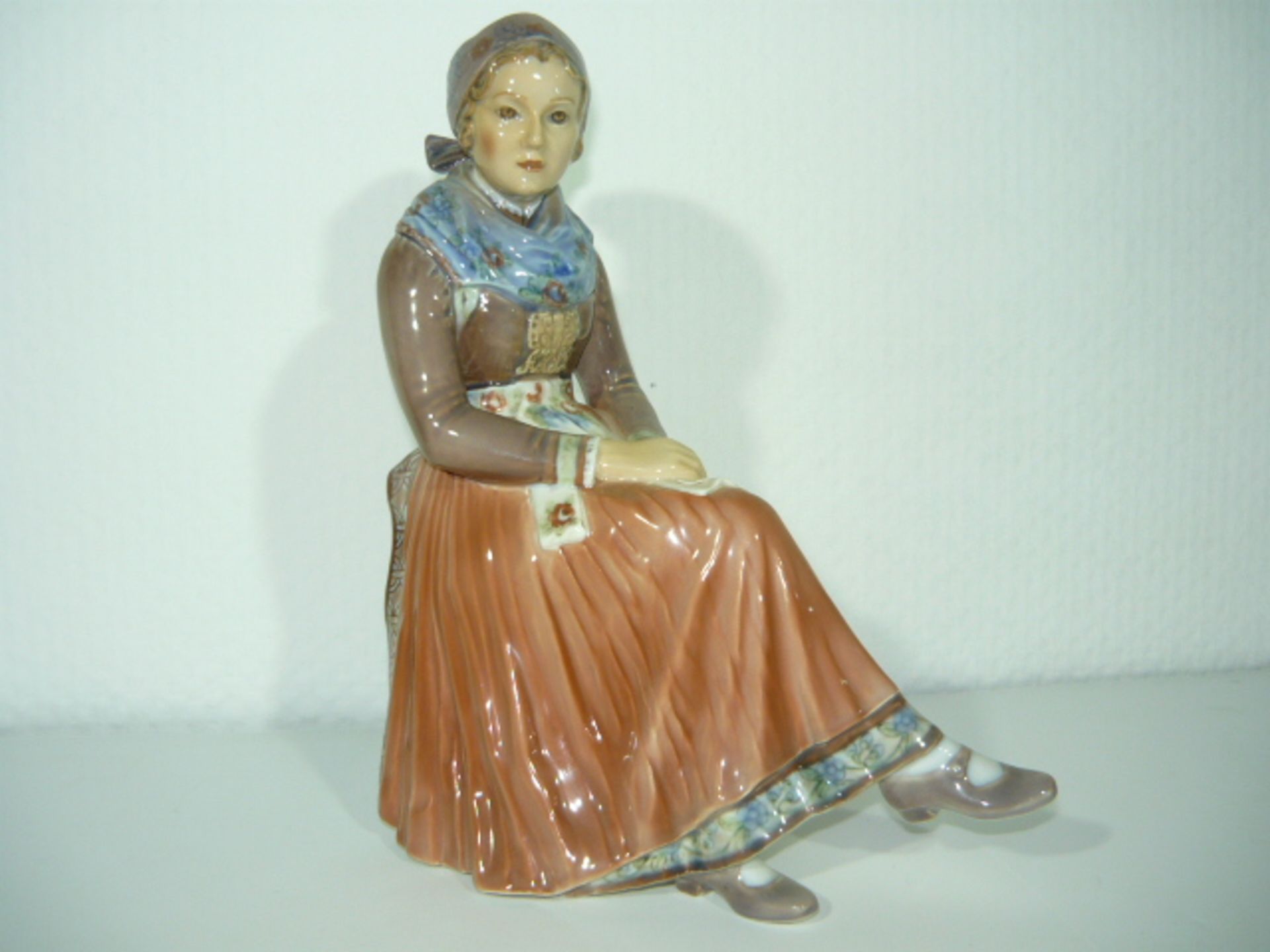 Dahl Jensen, Copenhagen. Große Porzellanfigur. Sitzende schöne Frau in Tracht. II.W. h. 22cm.