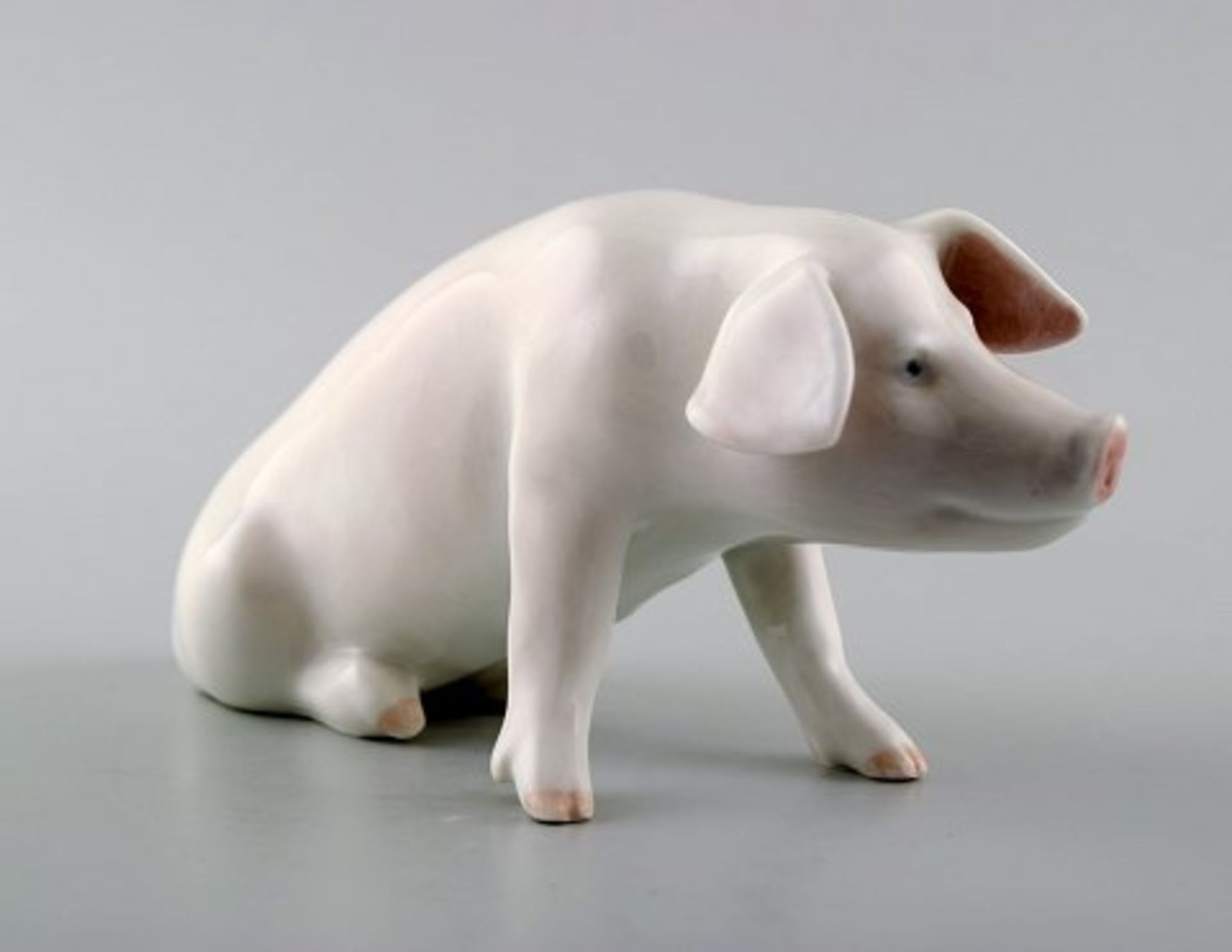 Royal Copenhagen. Sitzendes pinkes Schwein. Modell 1400. I.W. L. ca. 14cm.