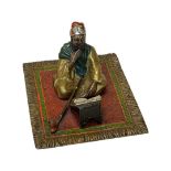 In the manner of Bergmann, a cold painted bronze figure of a seated Arab on a prayer mat