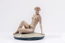 Porzellanfigur. Um 1930. Auf ovalem Grassockel sitzendes, nacktes Mädchen. H: 22 x 21,5 cm.