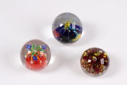 Konvolut. Drei Paperweight. Farbloses Glas mit Einschmelzungen wie Spinne, Blumen und Millefi