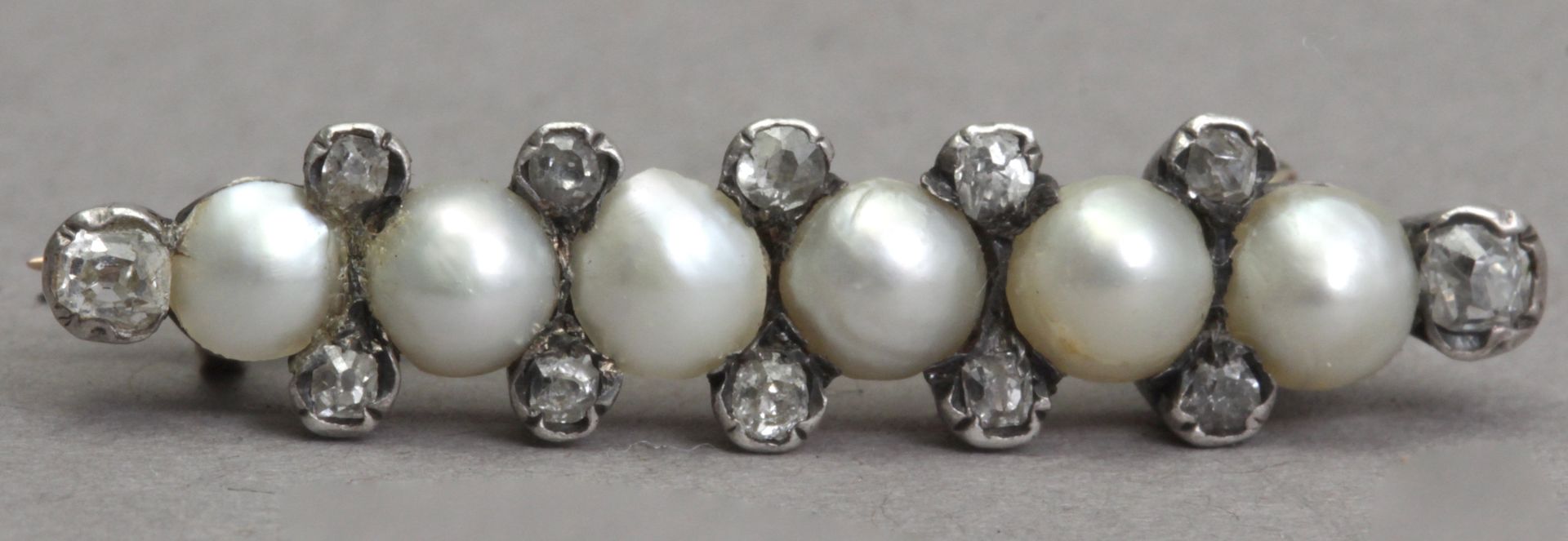 An early 20th century diamond and pearl tie pin in an 18k. gold and silver setting