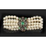 A four strand cultured pearl bracelet with a silver and gold clasp mounted with emeralds