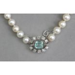 A cultured pearl necklace with an emerald and diamond brooch clasp