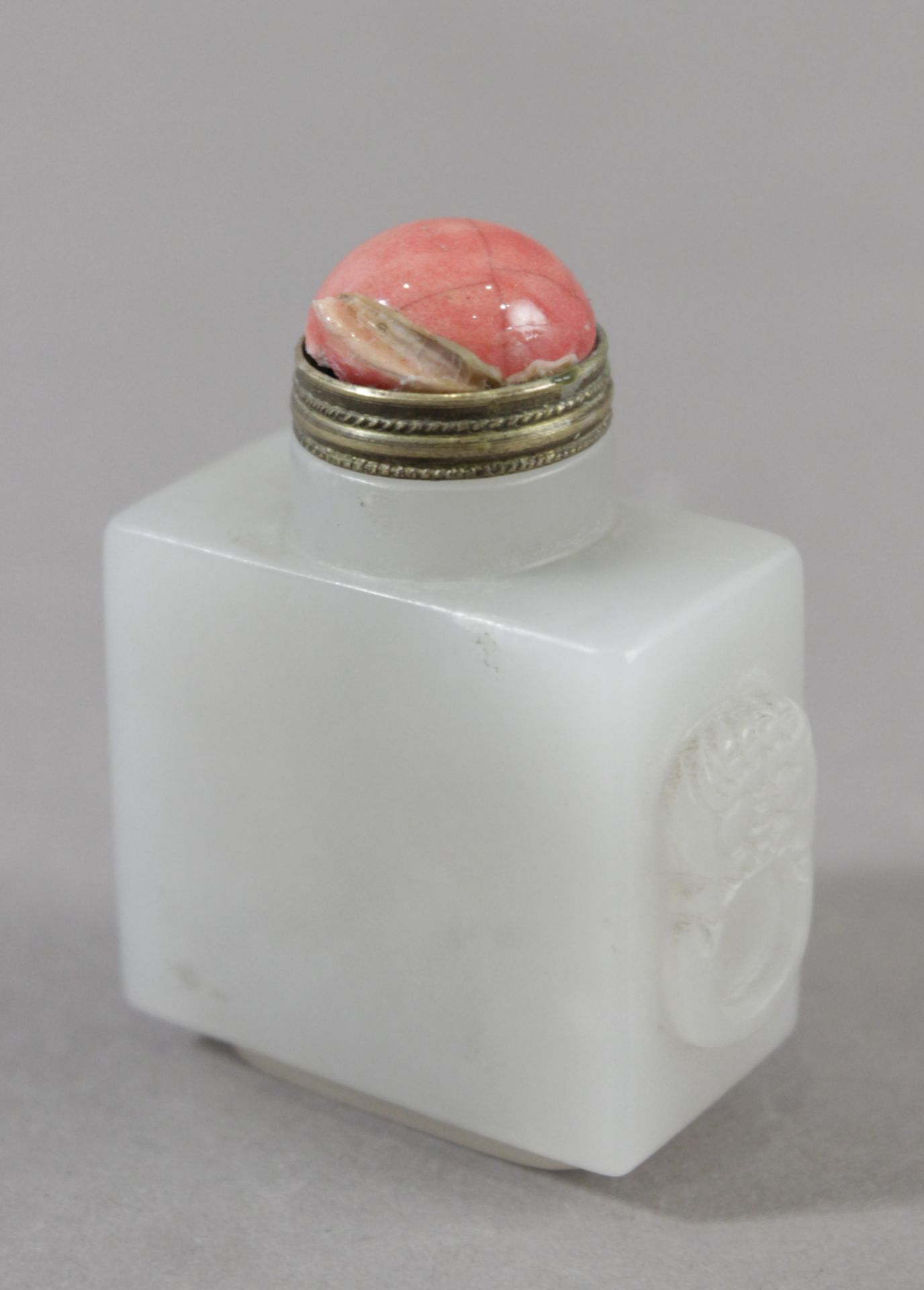 A 20th century Chinese snuff bottle in carved jade with coral top