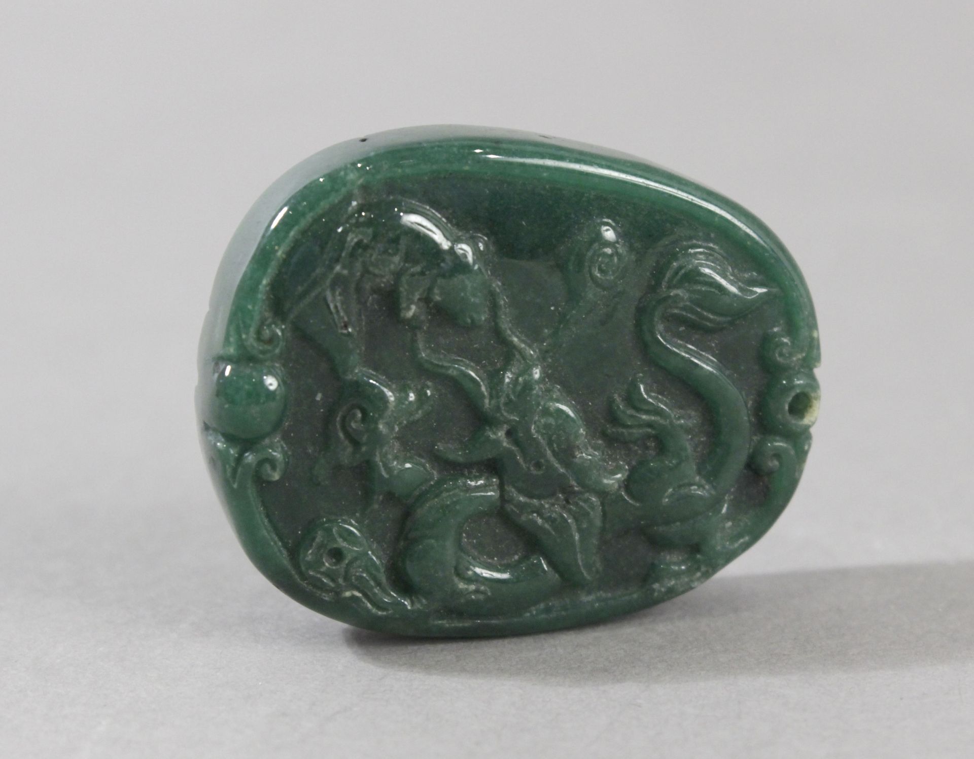 An early 20th century Chinese pendant in carved green jade