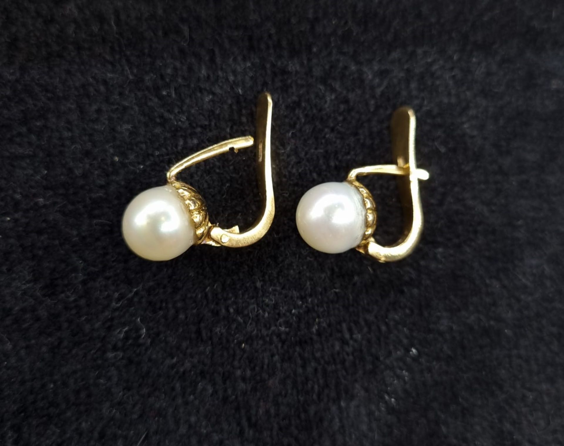 A pair of pearl earrings with an 18k. yellow gold setting