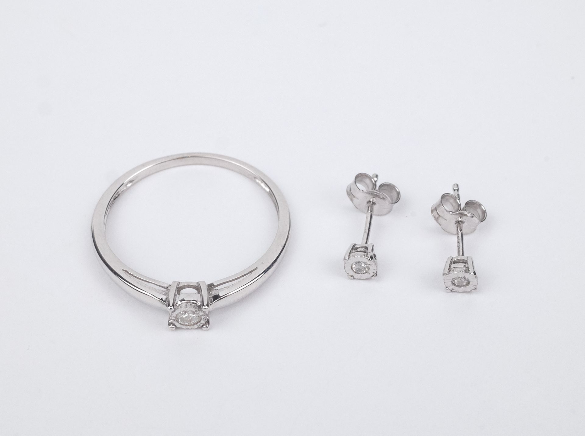 A set of diamond earrings and a solitaire ring