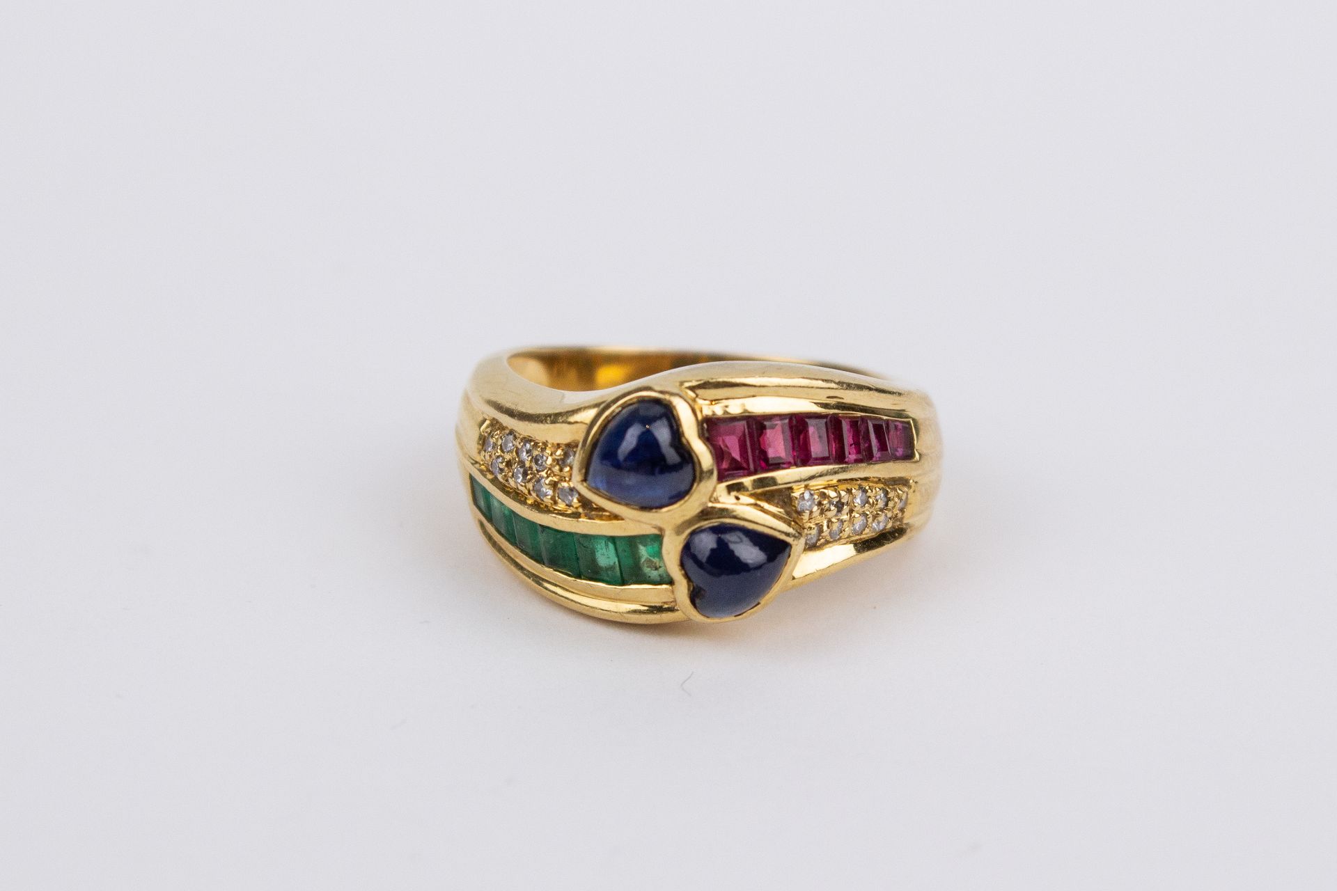 An 18k. yellow gold, sapphires, emeralds, rubies and diamonds ring