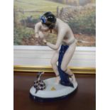 A Royal Dux tinted Bisque and glazed Porcelain Figure of a semi-nude snake charmer. On an oval base.