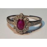 An 18ct gold ruby and diamond cluster ring. Ruby weight 0.41ct. Total diamond weight 0.16ct.