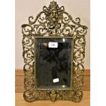 A cast brass easel mirror, with mask and scroll pierced border, 44cm.