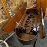 An unusual oval mahogany drinks trolley, the twin hinged top opening to reveal a rising bottle and