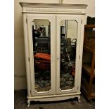 A white painted wardrobe with twin mirrored doors, the interior providing hanging and shelf space.