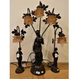 A bronze effect table lamp garniture, in the form of a lady holding a basket, triple pale pink