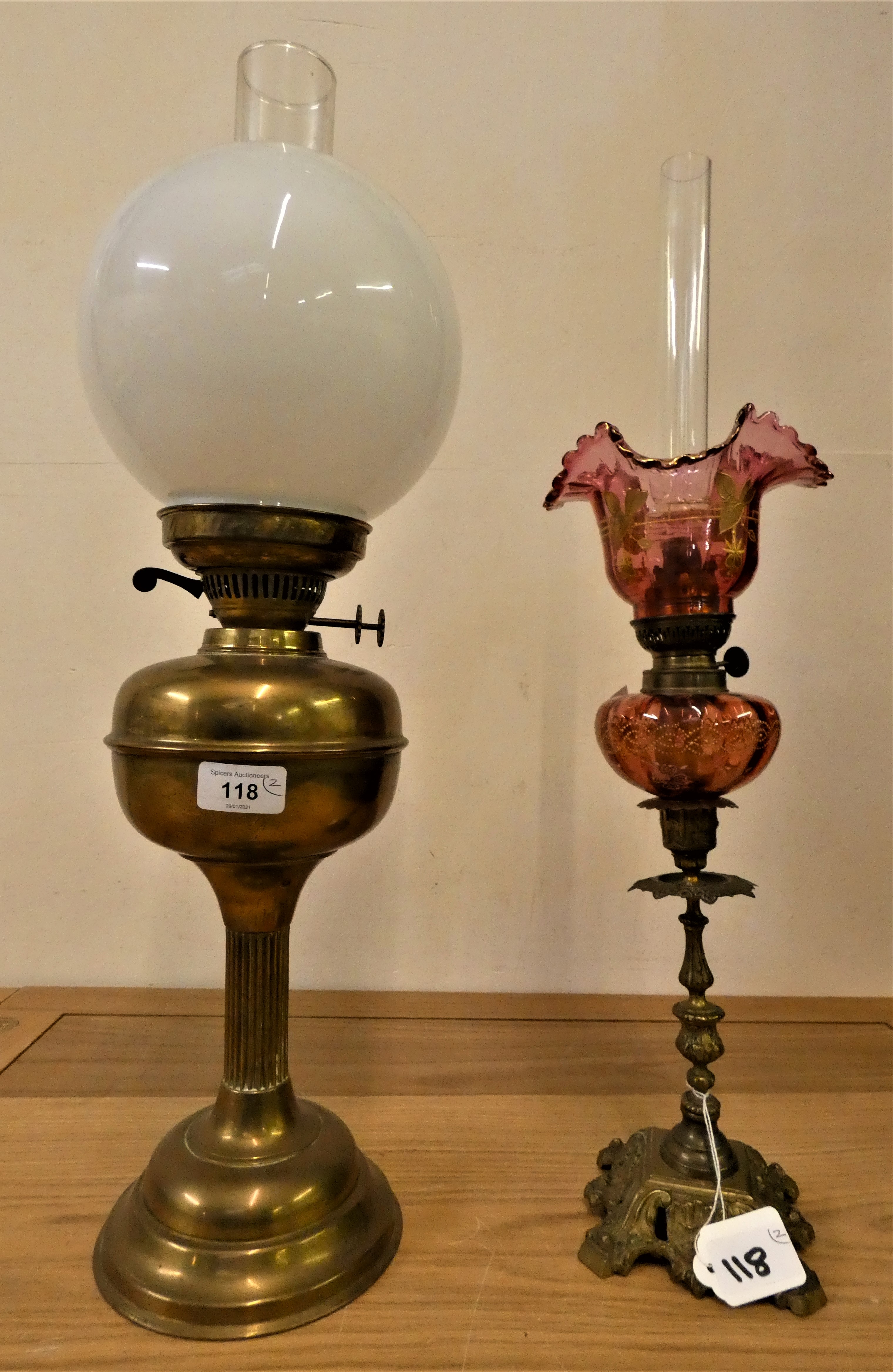 A brass oil lamp, with white glass shade, 60 cm, together with a cranberry glass oil lamp, 57 cm (