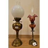 A brass oil lamp, with white glass shade, 60 cm, together with a cranberry glass oil lamp, 57 cm (