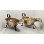 An Edwardian pair of Britannia Standard silver sauceboats, London 1903, raised on three pad feet,