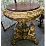 A gilt marble topped circular tripod table 55cm diameter, the heavily decorated base with cherubs to
