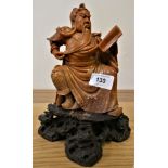 A Chinese soapstone figure of a seated man reading a book, Qing dynasty, raised on a brown hardstone
