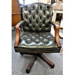 A green leather button back swivel office chair.