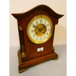 An oak inlaid mantle clock with cream and brass dial, brass feet and detailing with arched top. 32cm