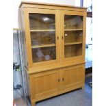 A light oak display cabinet with two glazed doors over two cupboard doors, 150 x 46 x 209 cm.