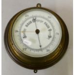 A circular brass cased barometer mounted on hardwood base.