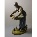 A large late 19th Century continental ceramic glazed figure of a woman feeding chickens. 60cm tall.