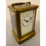 A brass cased manual wind carriage clock with white enamelled dial and Roman numerals.