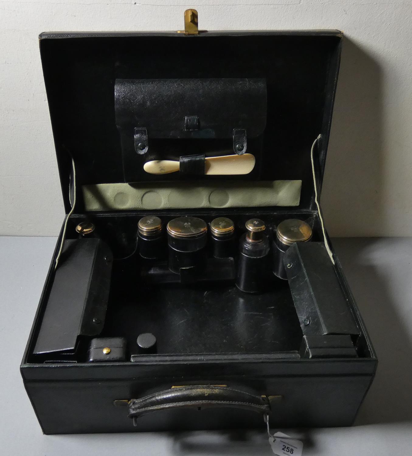 A French green leather travelling case, with fitted interior, seven silver gilt topped bottles by