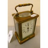 A brass cased manual wind carriage clock with white enameled dial and roman numerals.