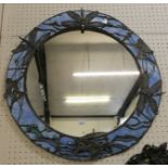 A circular mirror by John Leathwood, the blue glass surround supported by metalwork in the form of