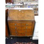 A burr walnut bow fronted writing bureau, the fall front with inset skiver and fitted interior, over