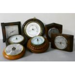 A collection of six aneroid wall mounted barometers.