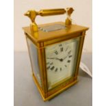 A brass cased manual wind carriage clock with white enamelled dial and Roman numerals, movement