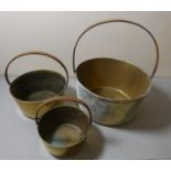 A set of three graduated brass jam pans (largest 36cm diameter) brass plaques, brass side table,