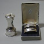 A silver pepper grinder, London 1928 and a pair of silver napkin rings, London 1991, case.