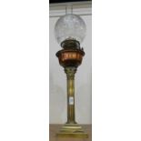 A brass column oil lamp with pink glass reservoir and pink glass shade.