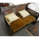 A Bergere settee with mahogany frame, carved symbols along the top rail, mustard seat cushions.