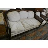 A mahogany framed Bergere suite, comprising settee, 174 cm wide and two armchairs, with cream
